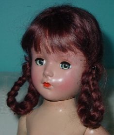 Close-up of a vintage doll with braided red hair and green eyes.