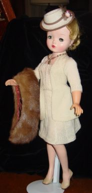A person in a white outfit holding a brown fur stole.