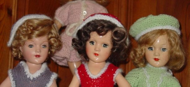 Vintage doll with curly hair in a red dress and pink hat.